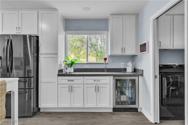 5486 Alfred Dr, Las Vegas, NV 89108 - kitchen with freestanding refrigerator, beverage cooler, white cabinets, and dark countertops