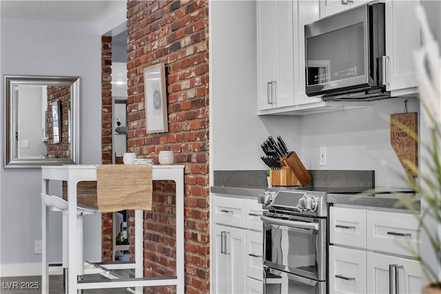 5486 Alfred Dr, Las Vegas, NV 89108 - kitchen with electric stove, white cabinets, dark countertops, and brick wall