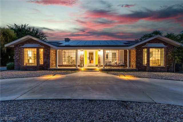 5486 Alfred Dr, Las Vegas, NV 89108 - back of house at dusk with a porch, brick siding, and solar panels
