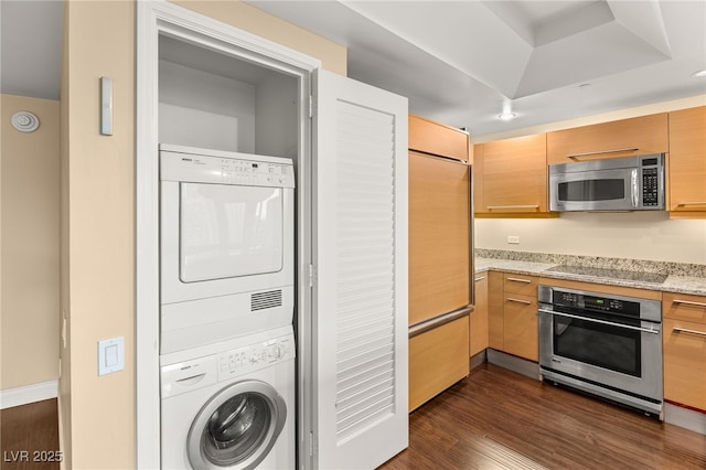 222 Karen Ave Unit 1702, Las Vegas, NV 89109 - kitchen featuring stainless steel appliances, stacked washing machine and dryer, dark wood finished floors, and light stone countertops