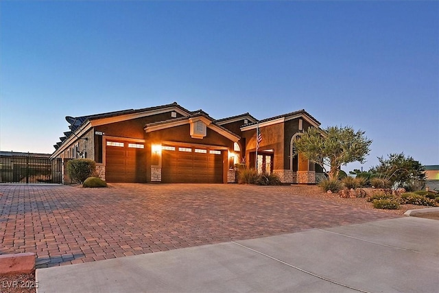 6208 W Rome Blvd, Las Vegas, NV 89131 - view of front of home featuring stone siding, decorative driveway, an attached garage, and stucco siding