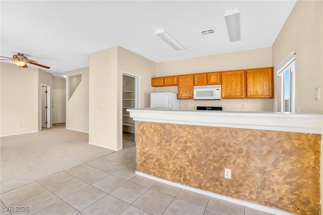 2558 Lazy Saddle Dr, Henderson, NV 89002 - kitchen featuring white appliances, brown cabinets, light countertops, light carpet, and ceiling fan