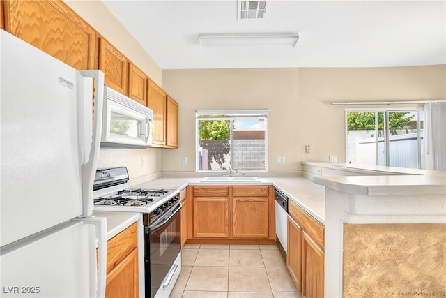 2558 Lazy Saddle Dr, Henderson, NV 89002 - kitchen with white appliances, a peninsula, light countertops, and light tile patterned floors