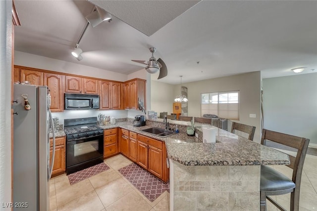 105 Lighthouse Dr Unit 105, Boulder City, NV 89005 - kitchen featuring black appliances, a kitchen breakfast bar, a peninsula, stone counters, and light tile patterned floors
