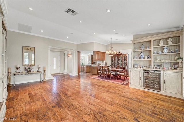 5224 Painted Lakes Way, Las Vegas, NV 89149 - living room featuring wine cooler, ornate columns, crown molding, wood finished floors, and a chandelier