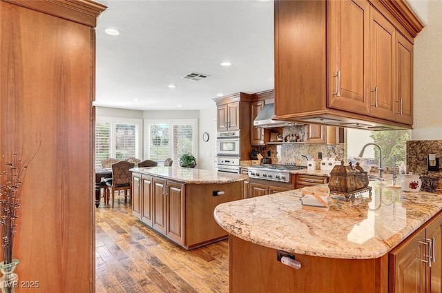 5224 Painted Lakes Way, Las Vegas, NV 89149 - kitchen with light wood-style flooring, brown cabinetry, decorative backsplash, light stone counters, and recessed lighting