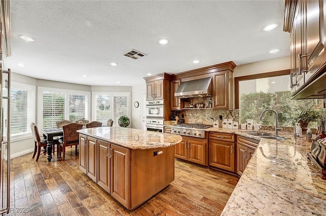 5224 Painted Lakes Way, Las Vegas, NV 89149 - kitchen with extractor fan, stainless steel gas cooktop, light stone countertops, a kitchen island, and wood finished floors