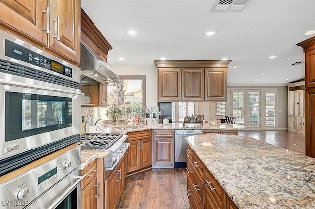 5224 Painted Lakes Way, Las Vegas, NV 89149 - kitchen with stainless steel appliances, dark wood finished floors, recessed lighting, light stone counters, and range hood
