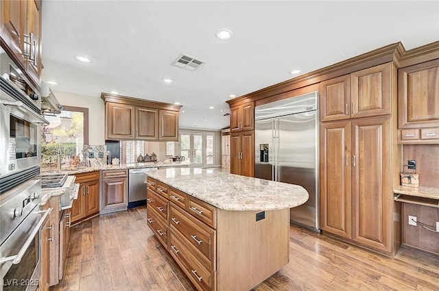 5224 Painted Lakes Way, Las Vegas, NV 89149 - kitchen with stainless steel appliances, hardwood / wood-style floors, a kitchen island, light stone countertops, and recessed lighting