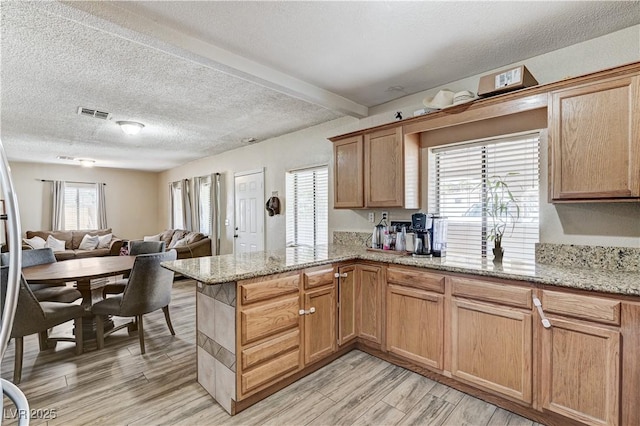 744 Mcknight St, Las Vegas, NV 89101 - kitchen with a peninsula, light wood-type flooring, open floor plan, a textured ceiling, and light stone counters