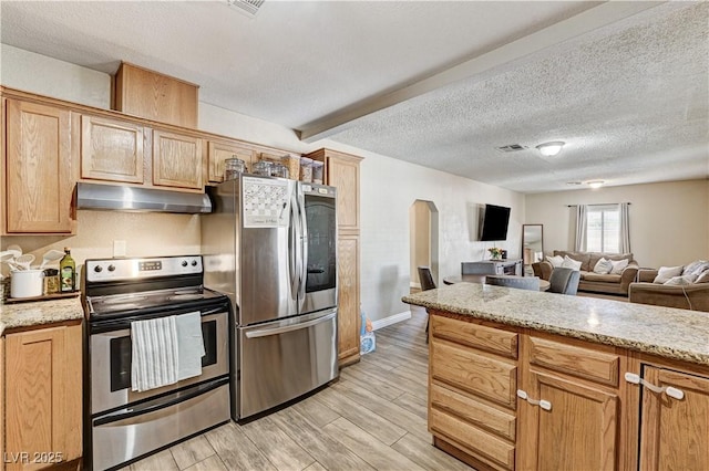 744 Mcknight St, Las Vegas, NV 89101 - kitchen featuring stainless steel appliances, under cabinet range hood, arched walkways, light wood-style floors, and a textured ceiling