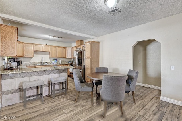 744 Mcknight St, Las Vegas, NV 89101 - dining area featuring arched walkways, a textured ceiling, and light wood-style flooring
