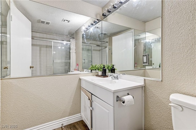 744 Mcknight St, Las Vegas, NV 89101 - bathroom with a textured wall, vanity, wood finished floors, a textured ceiling, and a tile shower