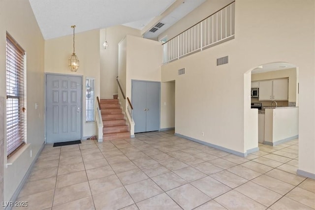1711 Ember Glow Cir, Las Vegas, NV 89119 - foyer entrance featuring a towering ceiling, light tile patterned floors, arched walkways, and stairway