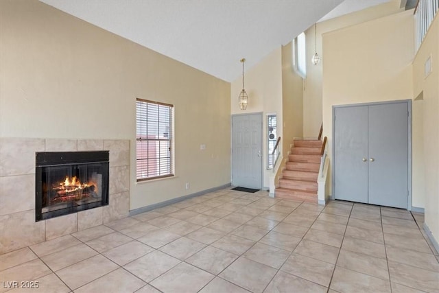 1711 Ember Glow Cir, Las Vegas, NV 89119 - entryway featuring high vaulted ceiling, light tile patterned floors, a tile fireplace, and stairway