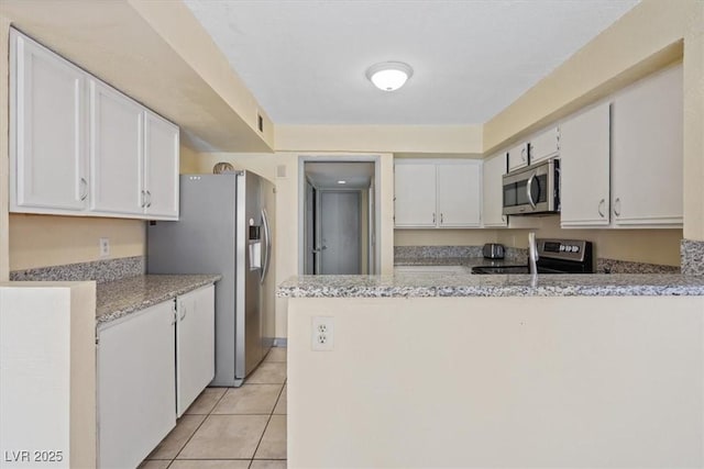1711 Ember Glow Cir, Las Vegas, NV 89119 - kitchen with stainless steel appliances, white cabinetry, a peninsula, light tile patterned floors, and light stone countertops