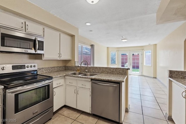 1711 Ember Glow Cir, Las Vegas, NV 89119 - kitchen with stainless steel appliances, a peninsula, light tile patterned floors, french doors, and white cabinetry
