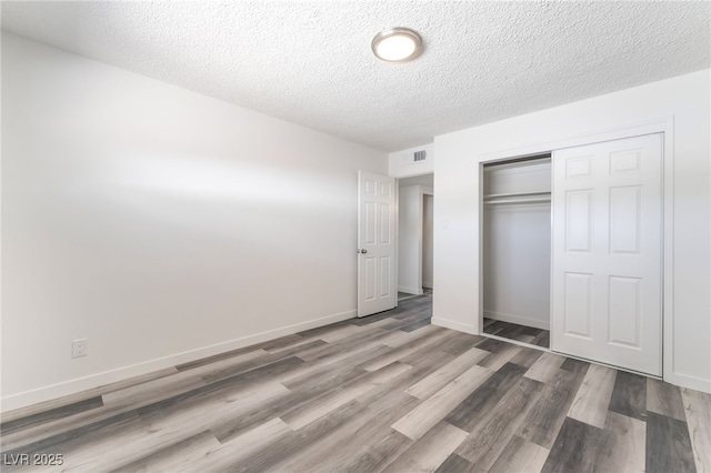 600 Berry Cir, Las Vegas, NV 89107 - unfurnished bedroom with a textured ceiling, a closet, and wood finished floors