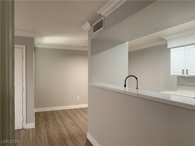 8101 W Flamingo Rd Unit 1102, Las Vegas, NV 89147 - kitchen featuring wood finished floors, crown molding, white cabinetry, and light countertops