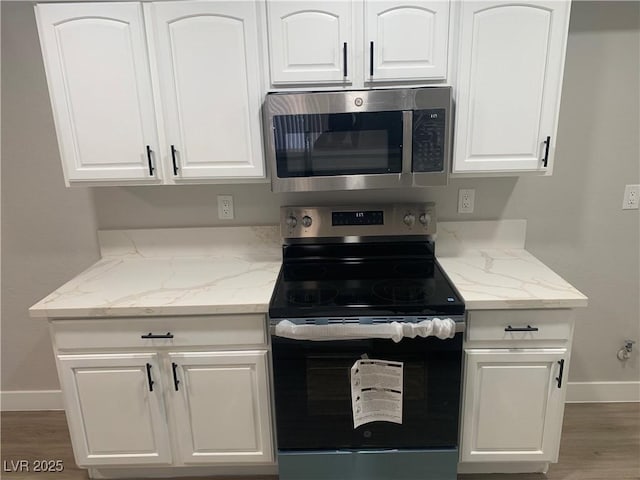 8101 W Flamingo Rd Unit 1102, Las Vegas, NV 89147 - kitchen with appliances with stainless steel finishes, light stone countertops, white cabinets, and wood finished floors