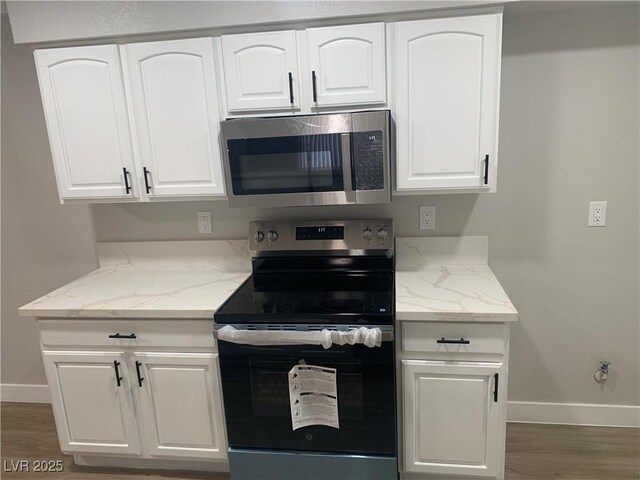 8101 W Flamingo Rd Unit 1102, Las Vegas, NV 89147 - kitchen featuring stainless steel appliances, light stone counters, white cabinets, and wood finished floors