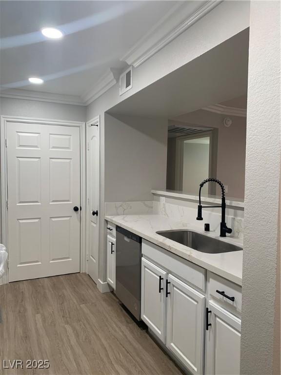 8101 W Flamingo Rd Unit 1102, Las Vegas, NV 89147 - kitchen with stainless steel dishwasher, crown molding, wood finished floors, white cabinetry, and light stone countertops