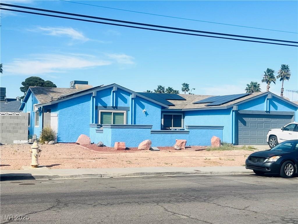 3664 Rawhide St, Las Vegas, NV 89120 - view of front of house featuring an attached garage, solar panels, and stucco siding