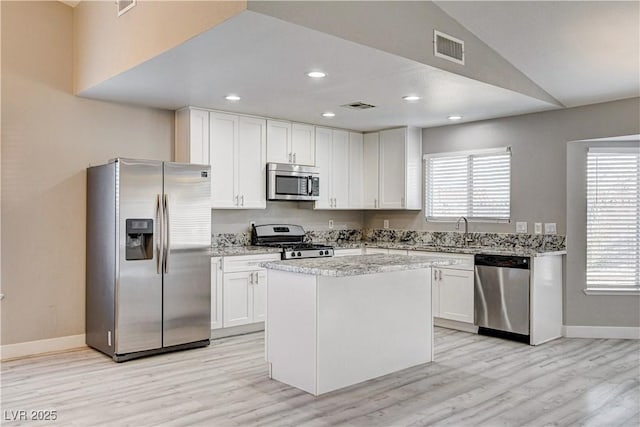 8517 Soneto Ln, Las Vegas, NV 89117 - kitchen featuring stainless steel appliances, light wood-style flooring, white cabinetry, light stone counters, and a kitchen island