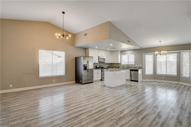 8517 Soneto Ln, Las Vegas, NV 89117 - kitchen featuring appliances with stainless steel finishes, a chandelier, open floor plan, vaulted ceiling, and light wood-type flooring