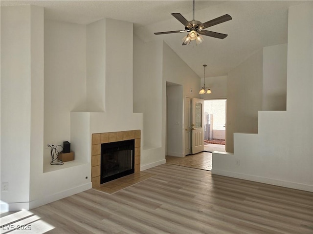 6636 Old Oxford Ave, Las Vegas, NV 89108 - unfurnished living room with light wood-style floors, a tiled fireplace, high vaulted ceiling, and ceiling fan