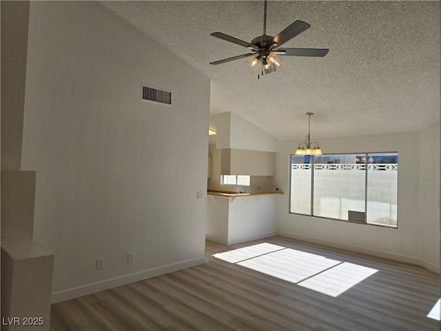 6636 Old Oxford Ave, Las Vegas, NV 89108 - spare room featuring a textured ceiling, lofted ceiling, wood finished floors, a chandelier, and ceiling fan