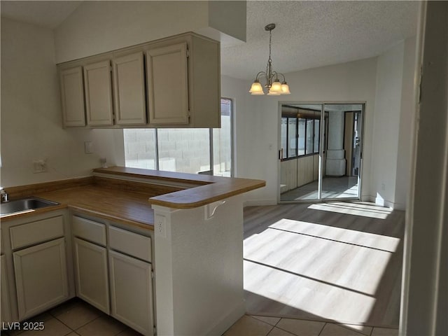 6636 Old Oxford Ave, Las Vegas, NV 89108 - kitchen with a chandelier, dark countertops, a textured ceiling, a peninsula, and hanging light fixtures