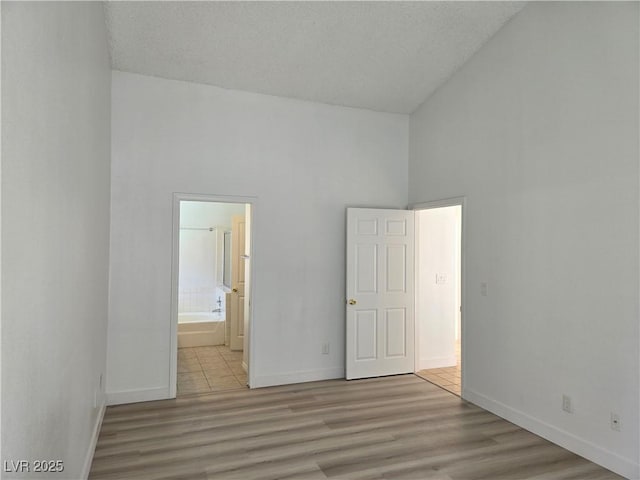 6636 Old Oxford Ave, Las Vegas, NV 89108 - unfurnished bedroom with wood finished floors, high vaulted ceiling, a textured ceiling, and connected bathroom