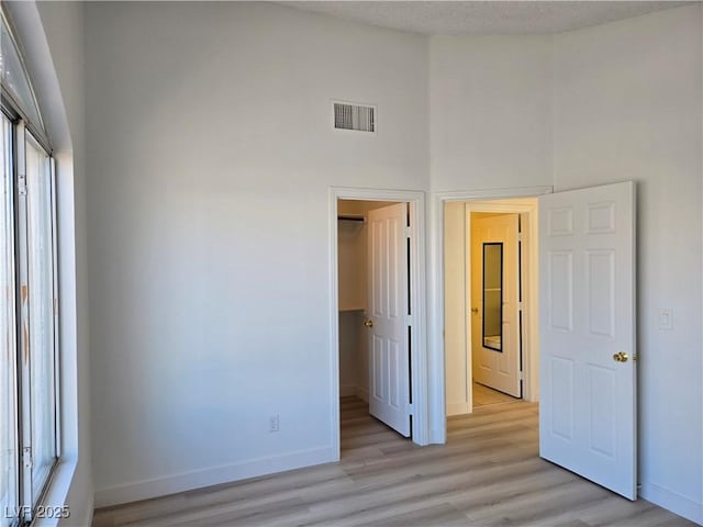 6636 Old Oxford Ave, Las Vegas, NV 89108 - unfurnished bedroom with a closet, a towering ceiling, light wood-style floors, and a spacious closet