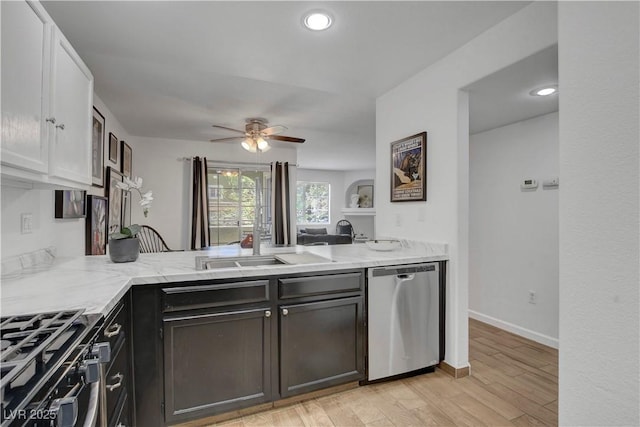 7950 W Flamingo Rd Unit 1042, Las Vegas, NV 89147 - kitchen featuring stainless steel appliances, ceiling fan, light stone counters, a peninsula, and light wood-style flooring