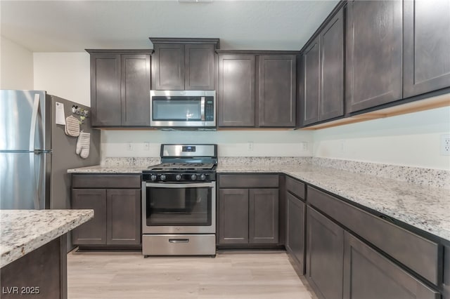 518 Descubir Ave, North Las Vegas, NV 89081 - kitchen featuring appliances with stainless steel finishes, dark brown cabinets, light wood finished floors, and light stone counters