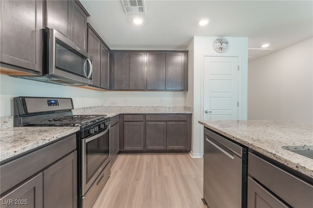 518 Descubir Ave, North Las Vegas, NV 89081 - kitchen with appliances with stainless steel finishes, light wood-style flooring, dark brown cabinetry, light stone counters, and recessed lighting