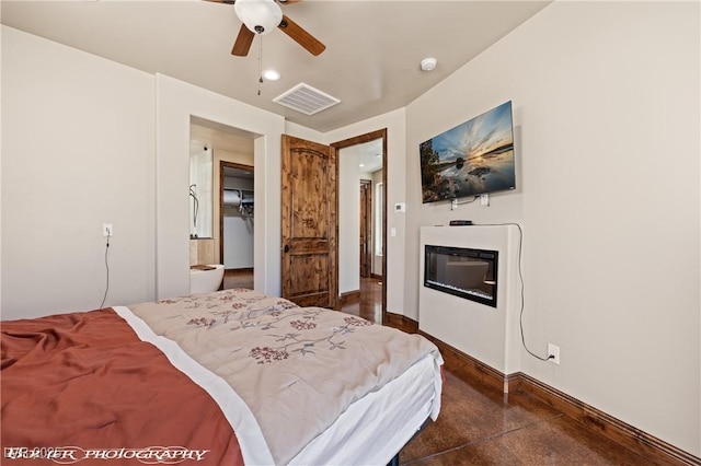 479 Apogee Crst, Mesquite, NV 89027 - bedroom with a glass covered fireplace, concrete flooring, a walk in closet, a ceiling fan, and recessed lighting