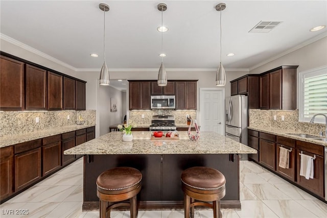 1304 Fantastic Ct, North Las Vegas, NV 89081 - kitchen with appliances with stainless steel finishes, a kitchen island, decorative backsplash, recessed lighting, and ornamental molding