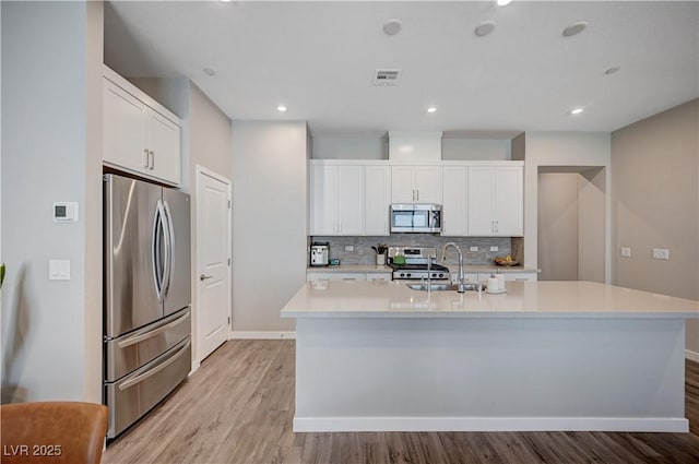 3358 Via Strada St, Henderson, NV 89044 - kitchen with appliances with stainless steel finishes, tasteful backsplash, light wood-style floors, light countertops, and white cabinets