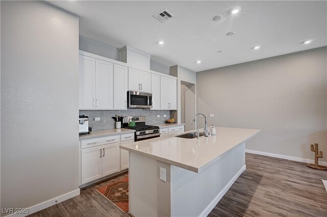 3358 Via Strada St, Henderson, NV 89044 - kitchen featuring stainless steel appliances, backsplash, dark wood-type flooring, a kitchen island with sink, and white cabinets