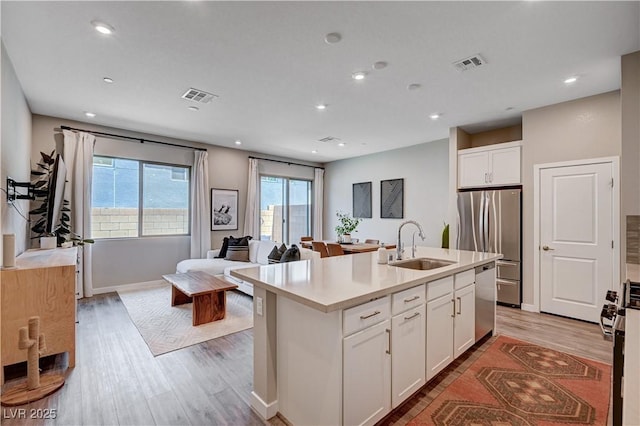 3358 Via Strada St, Henderson, NV 89044 - kitchen featuring stainless steel appliances, light wood-style flooring, white cabinets, an island with sink, and open floor plan