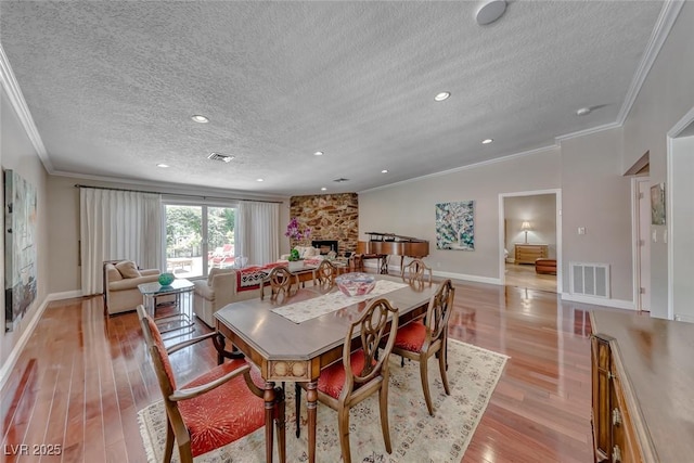 2101 Plaza Del Fuentes, Las Vegas, NV 89102 - dining room with crown molding, a textured ceiling, a fireplace, and light wood-style flooring