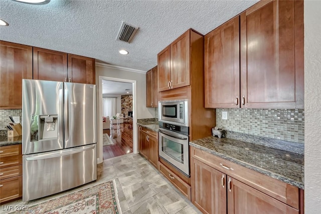 2101 Plaza Del Fuentes, Las Vegas, NV 89102 - kitchen with appliances with stainless steel finishes, dark stone countertops, crown molding, tasteful backsplash, and brown cabinetry