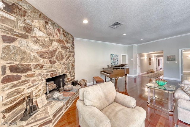 2101 Plaza Del Fuentes, Las Vegas, NV 89102 - living room featuring crown molding, wood finished floors, a textured ceiling, a stone fireplace, and recessed lighting