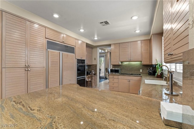 8215 Crow Valley Ln, Las Vegas, NV 89113 - kitchen with paneled fridge, stainless steel microwave, black electric stovetop, decorative backsplash, and light stone counters