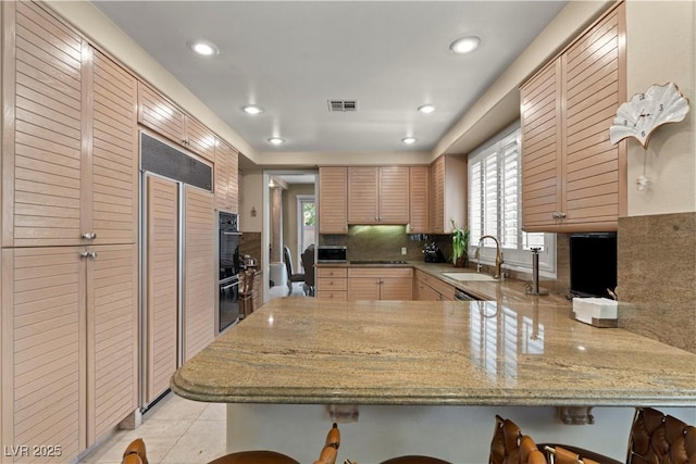 8215 Crow Valley Ln, Las Vegas, NV 89113 - kitchen with a peninsula, paneled refrigerator, a kitchen bar, tasteful backsplash, and recessed lighting