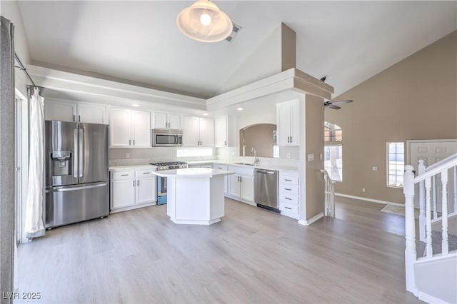 8712 Texas Bronco Ave, Las Vegas, NV 89129 - kitchen with appliances with stainless steel finishes, arched walkways, high vaulted ceiling, a kitchen island, and light countertops