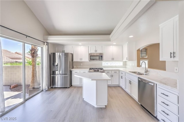 8712 Texas Bronco Ave, Las Vegas, NV 89129 - kitchen featuring appliances with stainless steel finishes, arched walkways, light wood finished floors, a center island, and light countertops