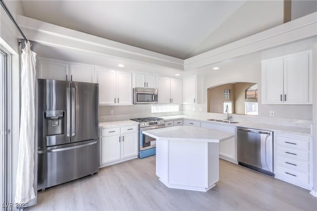 8712 Texas Bronco Ave, Las Vegas, NV 89129 - kitchen with stainless steel appliances, arched walkways, vaulted ceiling, light wood-style flooring, and light countertops